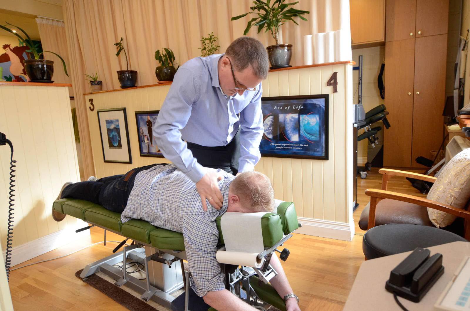 Chiropractor performing adjustment in therapy room.